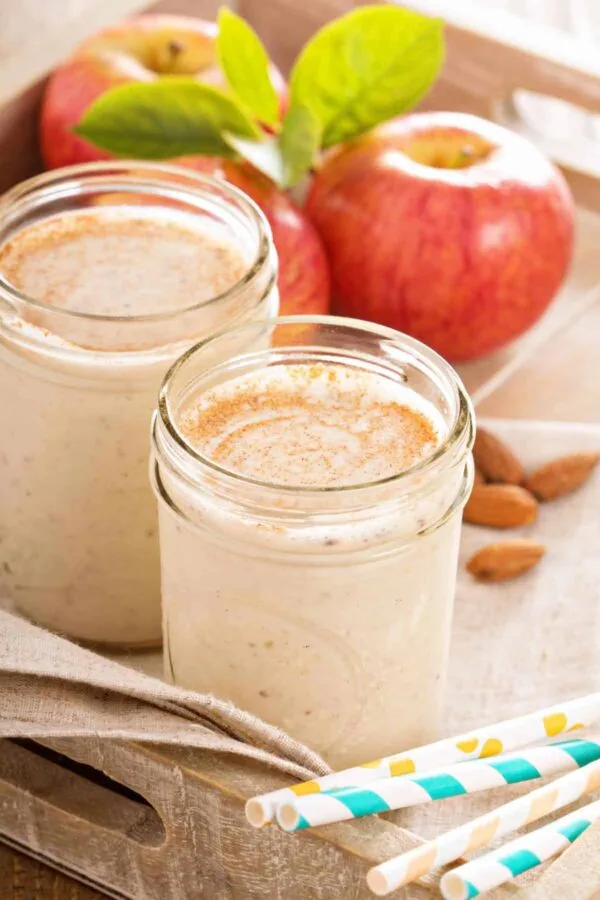 Cholesterol-Lowering Apple Cinnamon smoothie in a glass, on my kitchen counter, surrounded by fresh fruit and vegetables.