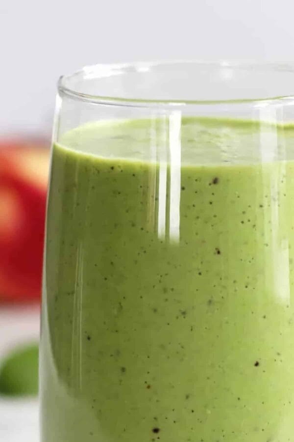 Easy Detox smoothie in a glass, on my kitchen counter, surrounded by fresh fruit and vegetables.