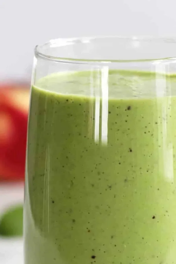 Easy Detox smoothie in a glass, on my kitchen counter, surrounded by fresh fruit and vegetables.
