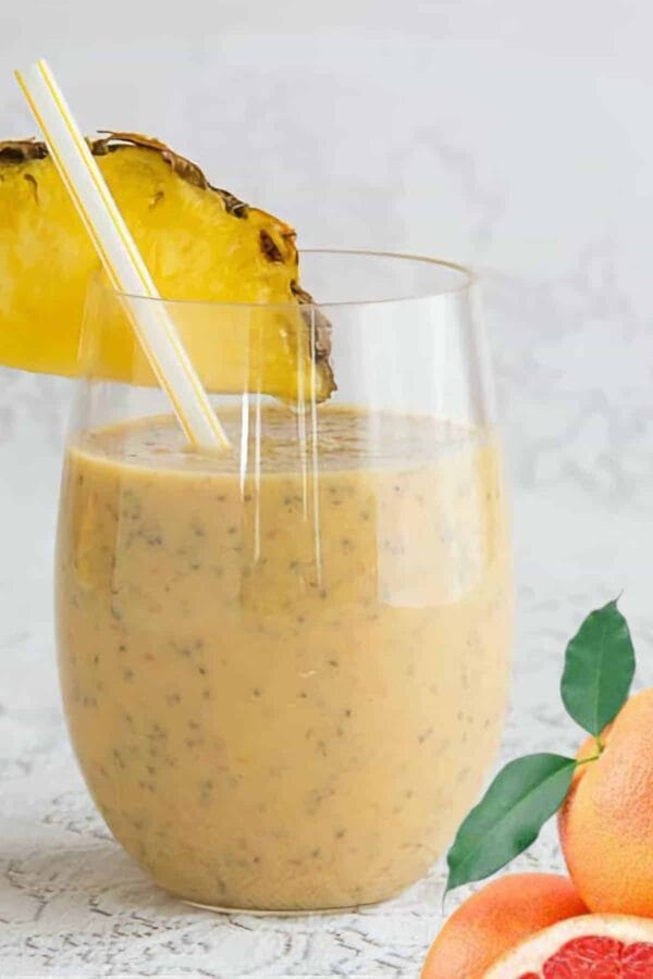 Grapefruit Detox smoothie in a glass, on my kitchen counter, surrounded by fresh fruit and vegetables.