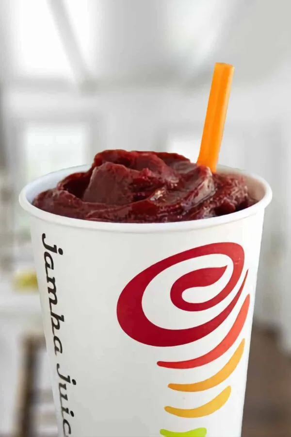 Jamba Juice Berry UpBEET smoothie in a glass, on my kitchen counter, surrounded by fresh berries and beets.