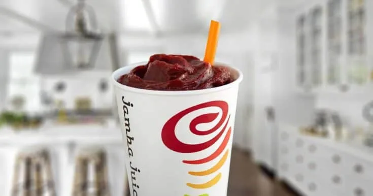 Jamba Juice Berry UpBEET smoothie in a glass, on my kitchen counter, surrounded by fresh berries and beets.