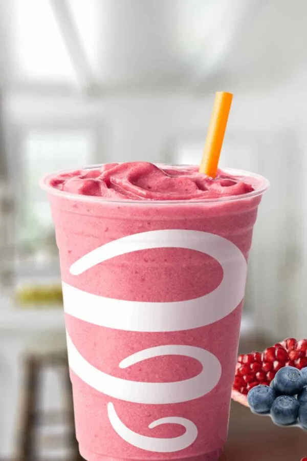 Jamba Juice Pomegranate Pick-Me-Up smoothie in a glass, on my kitchen counter, surrounded by pomegranate seeds and blueberries.