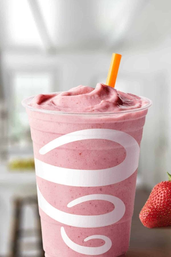 Jamba Juice Protein Berry Workout smoothie in a glass, on my kitchen counter, surrounded by fresh berries.