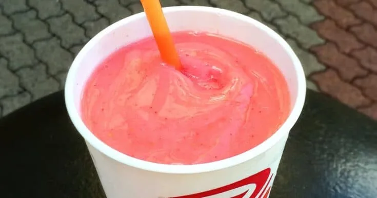 Jamba Juice Secret Menu Sour Patch Kids smoothie in a glass, outdoors.