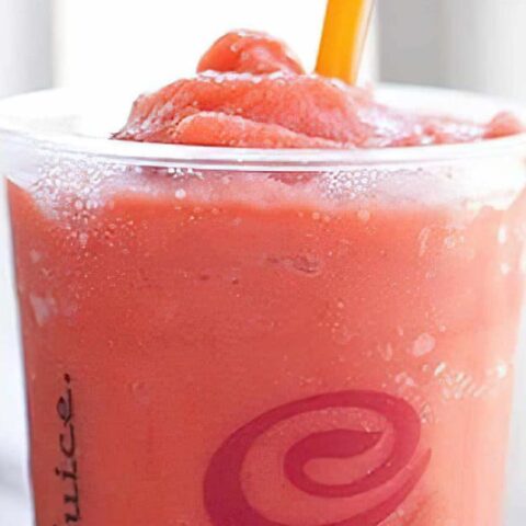 Jamba Juice Secret Menu Strawberry Pina Colada smoothie in a glass, on my kitchen counter, surrounded by fresh fruit.