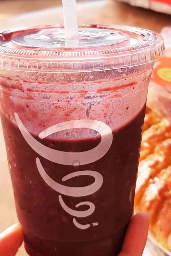 Jamba Juice Secret Menu Thank You Jesus smoothie in a glass, on my kitchen counter, surrounded by fresh fruit.