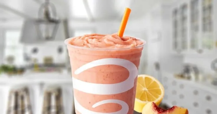 Jamba Juice Strawberry Surf Rider smoothie in a glass, on my kitchen counter, surrounded by fresh strawberries and citrus fruit.