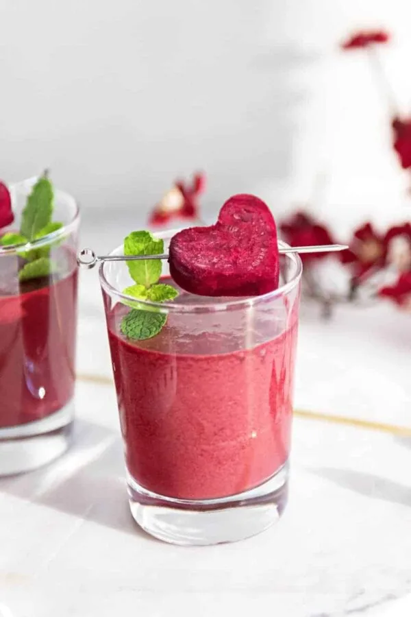 NutriBullet Pink Detox Blast smoothie in a glass, on my kitchen counter, surrounded by fresh fruit and vegetables.