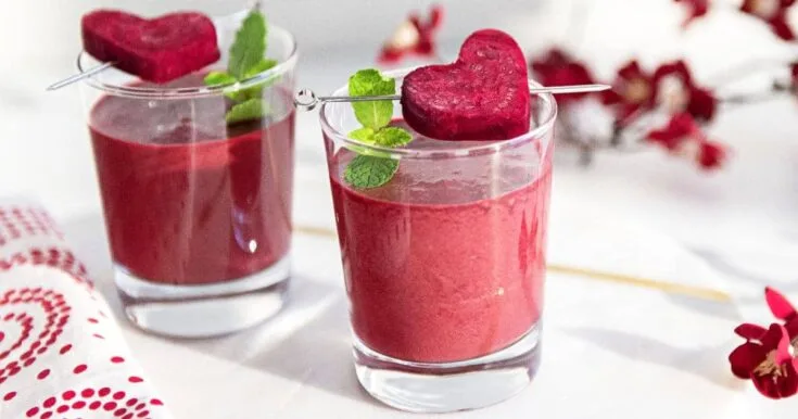 NutriBullet Pink Detox Blast smoothie in a glass, on my kitchen counter, surrounded by fresh fruit and vegetables.