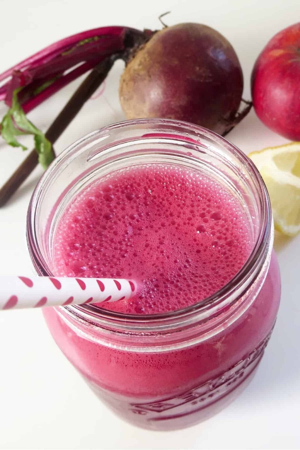 Realfood Liver Detox smoothie in a glass, on my kitchen counter, surrounded by fresh fruit and vegetables.