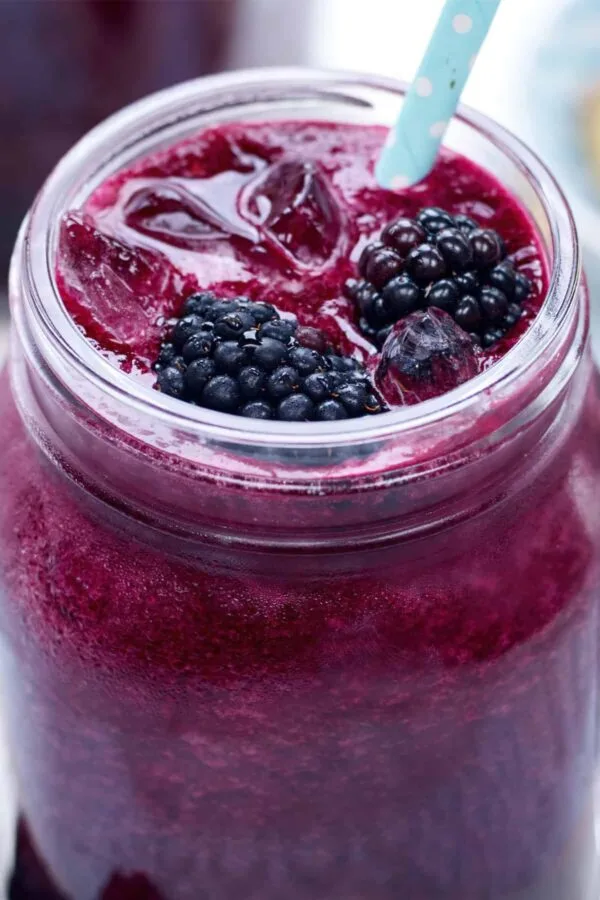 Vitamix Blackberry Beet smoothie in a glass, on my kitchen counter, surrounded by fresh fruit and vegetables.