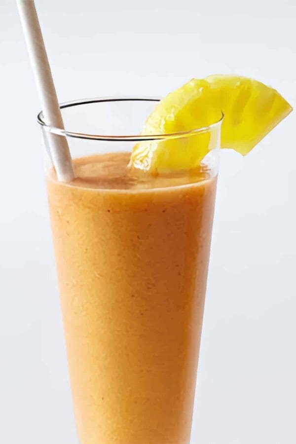 Vitamix Fruit Salad smoothie in a glass, on my kitchen counter, surrounded by fresh fruit and vegetables.