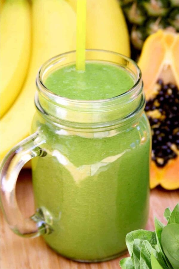 Vitamix Papaya Vanilla smoothie in a glass, on my kitchen counter, surrounded by fresh fruit and vegetables.