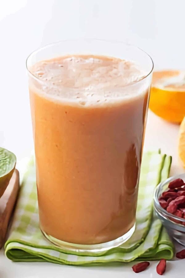 Ninja Blender 3-2-1 Immune Boost smoothie in a glass, on my kitchen counter, surrounded by fresh fruit.