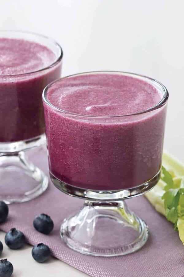 Ninja Blender Antioxidant Refresher smoothie in a glass, on my kitchen counter, surrounded by fresh fruit and vegetables.