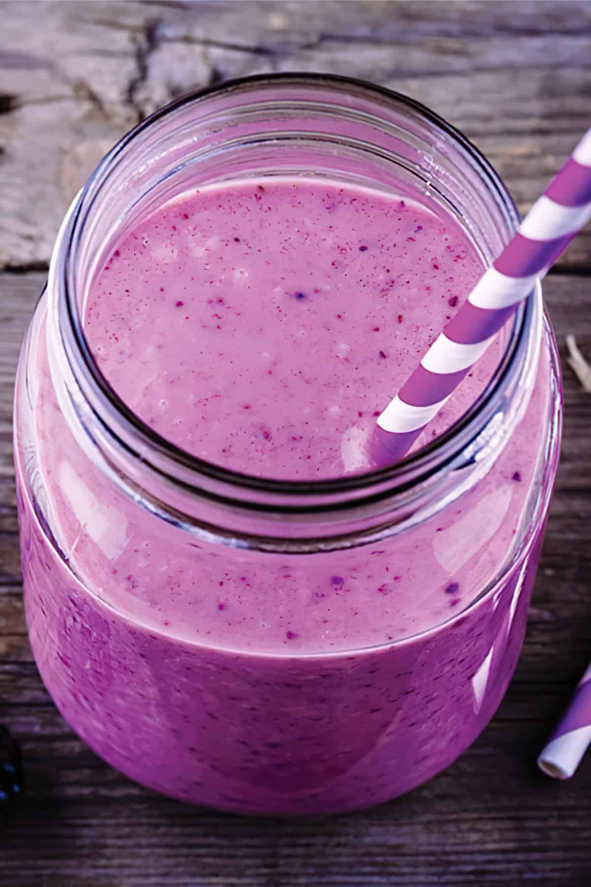 Ninja Blender Berry Almond smoothie in a glass, on my kitchen counter, surrounded by fresh berries and nuts.