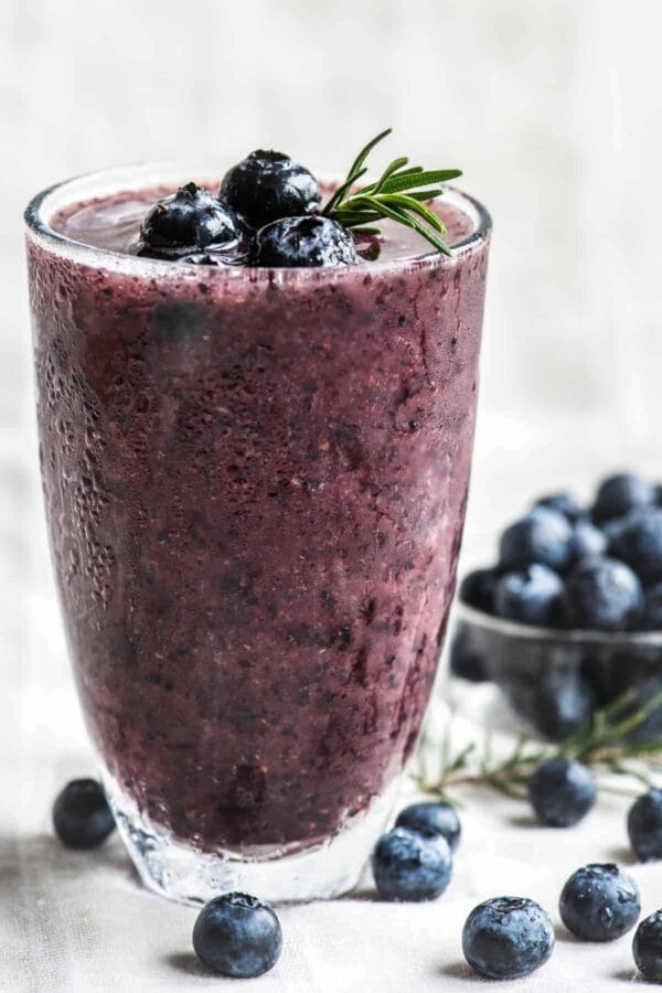 Ninja Blender Blueberry Power Blast Breakfast smoothie in a glass, on my kitchen counter, surrounded by fresh berries.