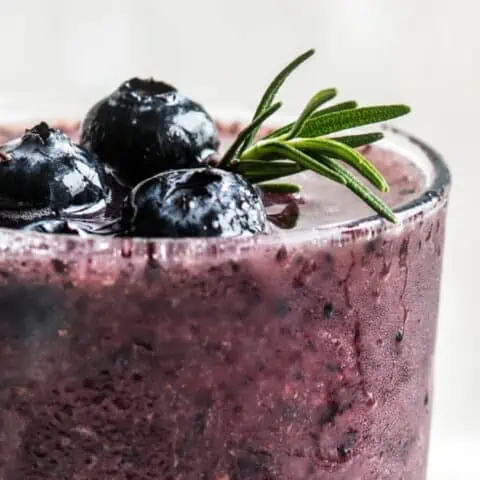 Ninja Blender Blueberry Power Blast Breakfast smoothie in a glass, on my kitchen counter, surrounded by fresh berries.