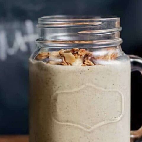 Ninja Blender Choco Nut Butter Protein smoothie in a glass, on my kitchen counter, surrounded by chocolate and nuts.