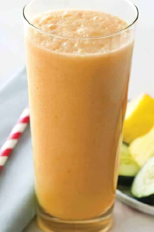 Ninja Blender Cool Cantaloupe Cucumber smoothie in a glass, on my kitchen counter, surrounded by fresh fruit.