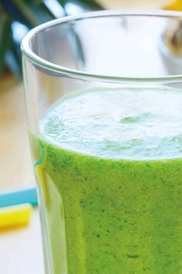 Ninja Blender Cucumber Pineapple Melon smoothie in a glass, on my kitchen counter, surrounded by fresh fruit.