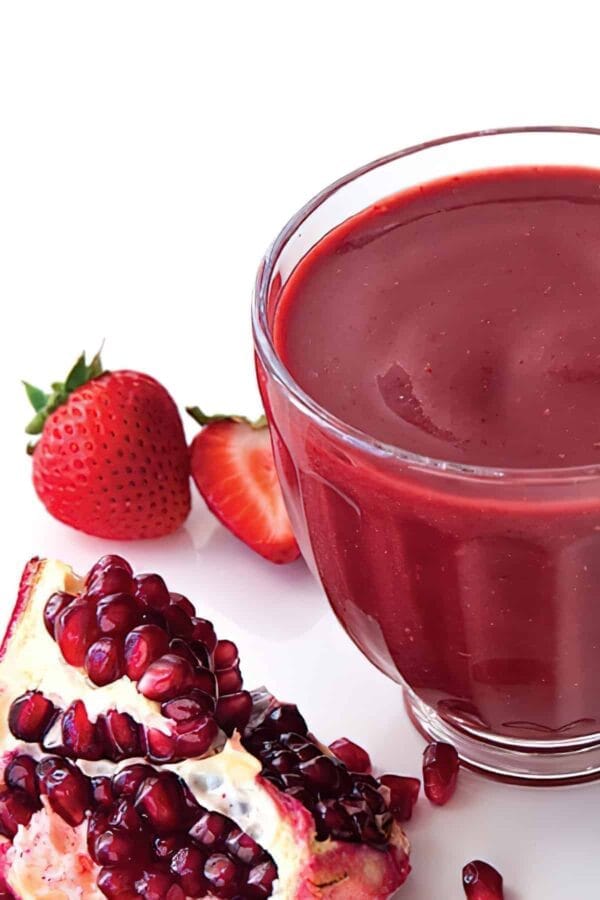 Ninja Blender Gingered Acai smoothie in a glass, on my kitchen counter, surrounded by fresh fruit.