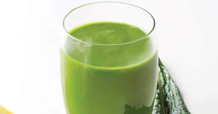 Ninja Blender Lean Green smoothie in a glass, on my kitchen counter, surrounded by fresh fruit and vegetables.