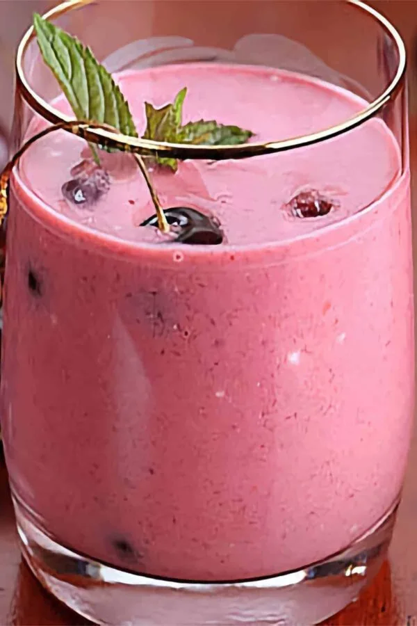 Ninja Blender Sweet Cherry smoothie in a glass, on my kitchen counter, surrounded by fresh fruit.