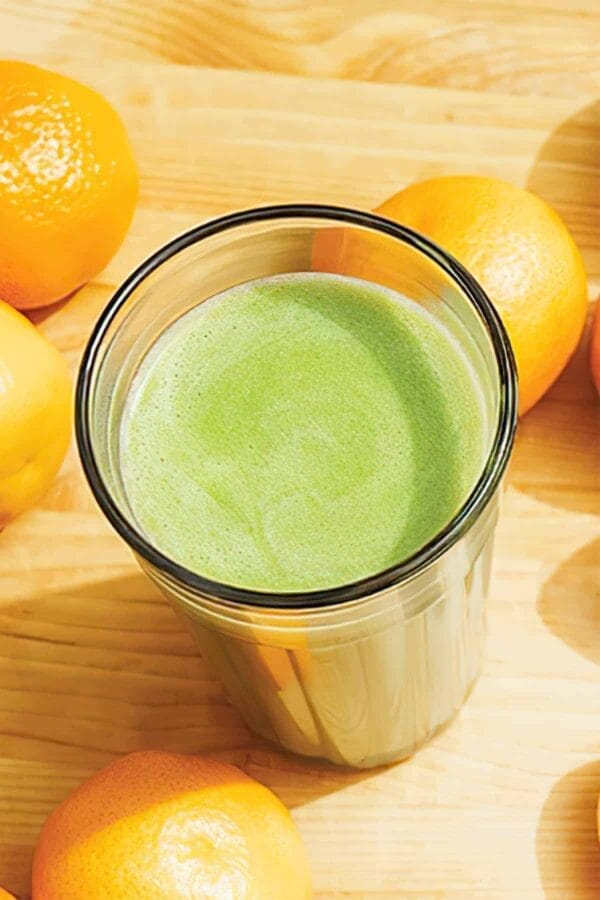 Ninja Blender Tangerine Protein Machine smoothie in a glass, on my kitchen counter, surrounded by fresh fruit.