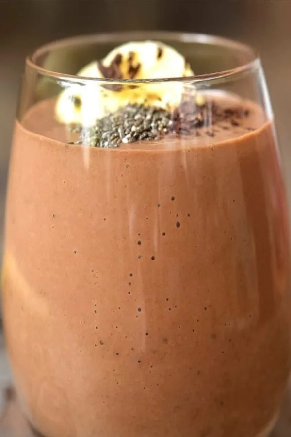 NutriBullet Banana Coffee smoothie in a glass, on my kitchen counter, surrounded by fresh fruit and coffee beans.