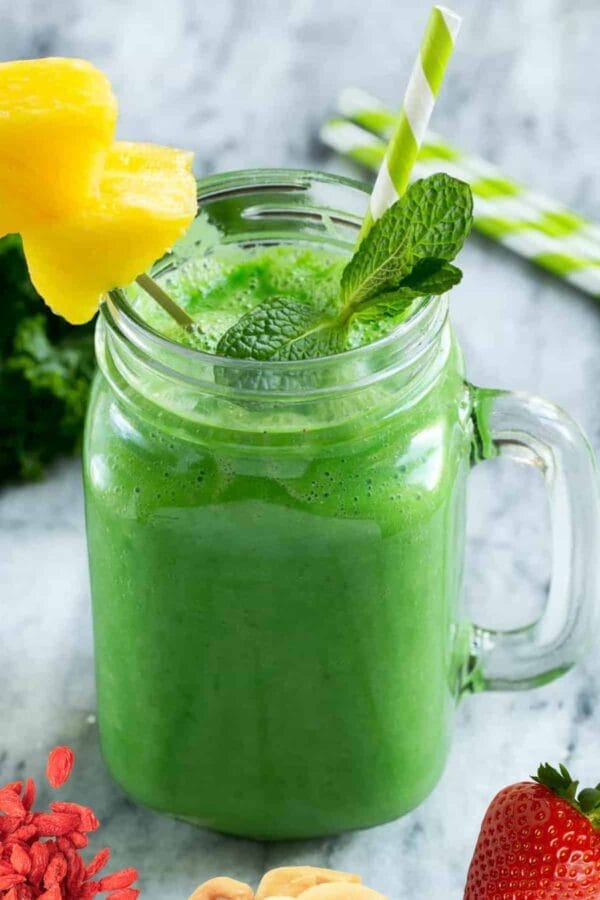 NutriBullet Beauty Blast smoothie in a glass, on my kitchen counter, surrounded by fresh fruit and vegetables.