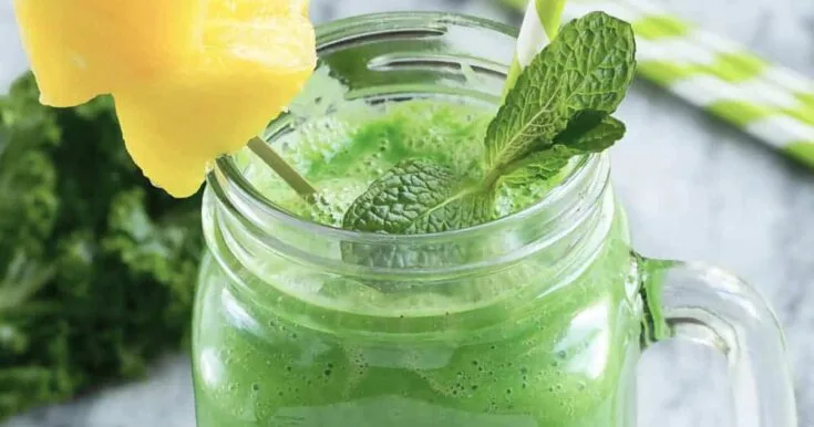 NutriBullet Beauty Blast smoothie in a glass, on my kitchen counter, surrounded by fresh fruit and vegetables.