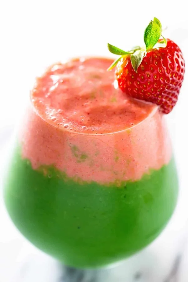 NutriBullet Berry Green Layered smoothie in a glass, on my kitchen counter, topped with a strawberry garnish.