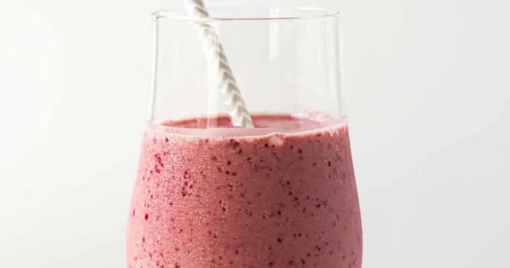 NutriBullet Cherry And Oats Bedtime smoothie in a glass, on my kitchen counter, surrounded by fresh fruit and rolled oats.