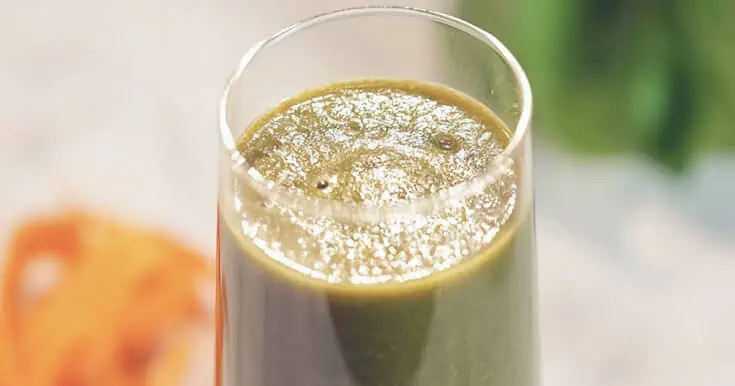 Paleo Diet smoothie in a glass, on my kitchen counter, surrounded by fresh vegetables.