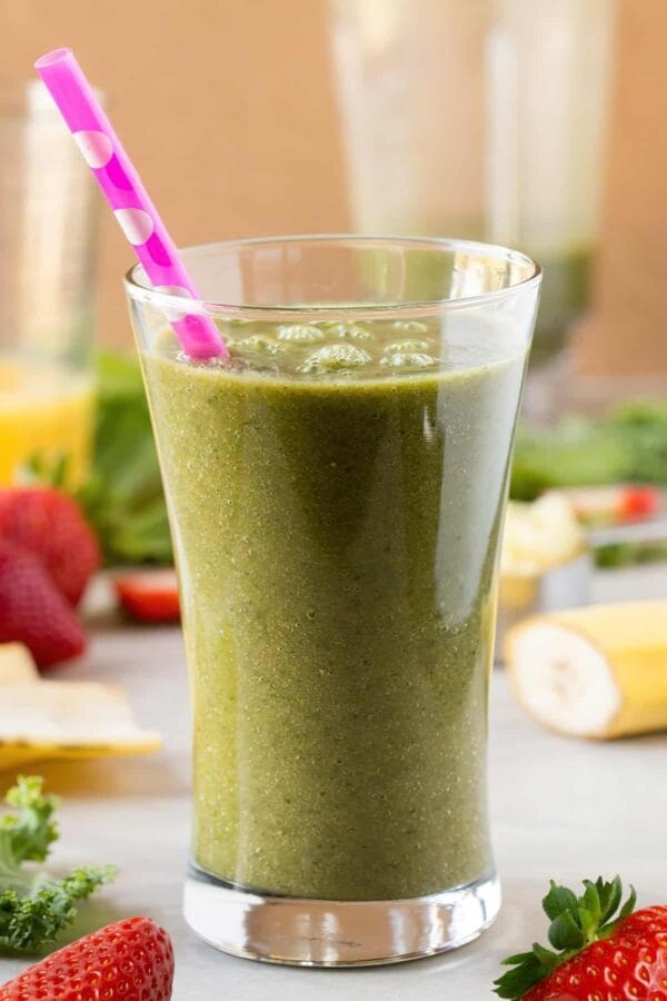 NutriBullet Creamy Green Strawberry Dream smoothie in a glass, on my kitchen counter, surrounded by fresh fruit and vegetables.