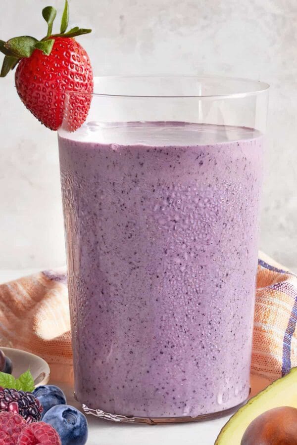 NutriBullet Heart Healthy Hemp smoothie in a glass, on my kitchen counter, surrounded by fresh fruit and berries.