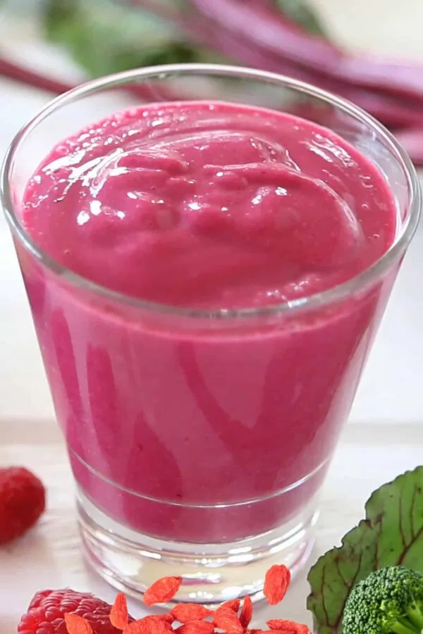 NutriBullet Hormone Helper smoothie in a glass, on my kitchen counter, surrounded by fresh fruit and vegetables.