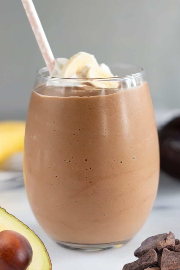 NutriBullet Loco Cocoa Recovery smoothie in a glass, on my kitchen counter, surrounded by fresh fruit and chocolate.