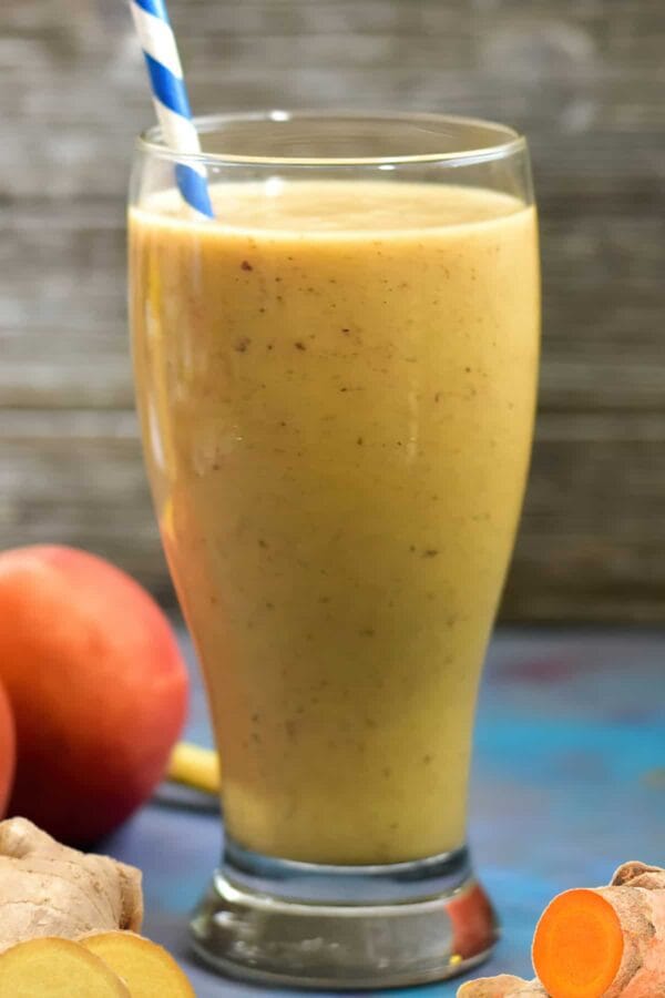 NutriBullet Lucky Charmed smoothie in a glass, on my kitchen counter, surrounded by fresh fruit.