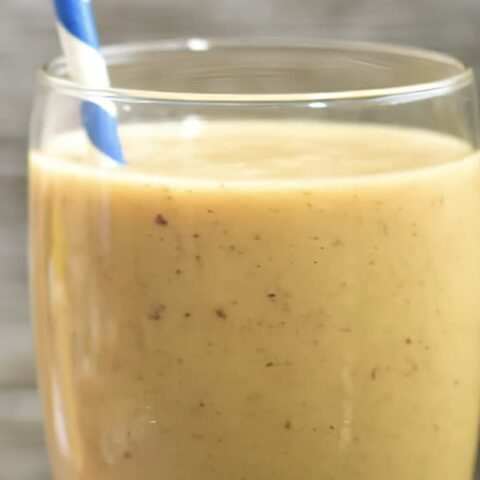 NutriBullet Lucky Charmed smoothie in a glass, on my kitchen counter, surrounded by fresh fruit.