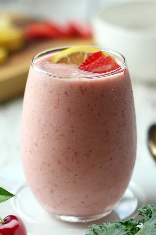 NutriBullet Pink Drink smoothie in a glass, on my kitchen counter, surrounded by fresh fruit and vegetables.