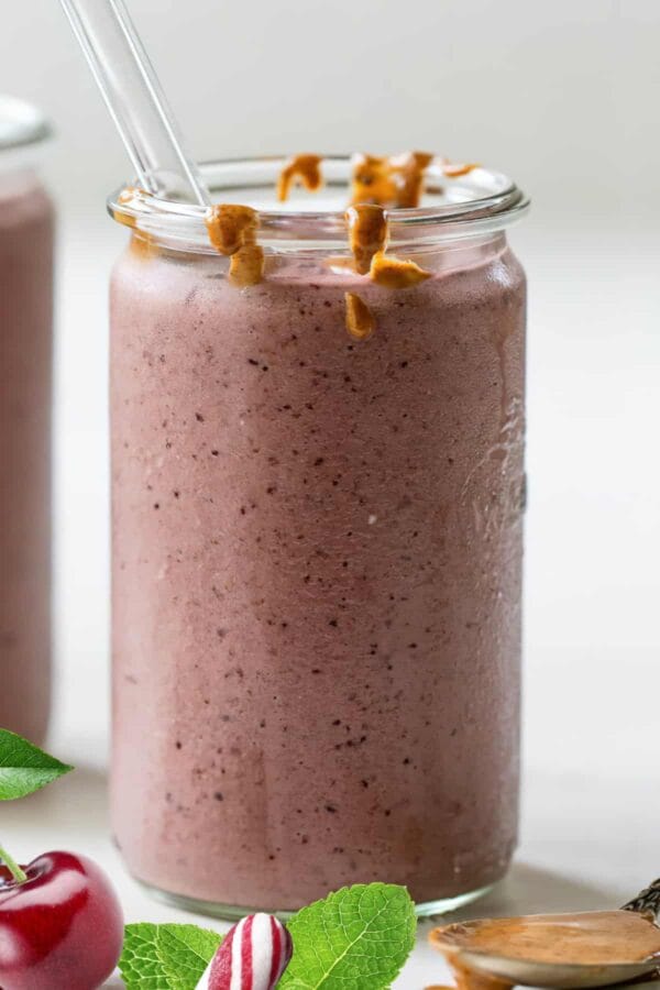 NutriBullet Pink Peppermint smoothie in a glass, on my kitchen counter, surrounded by fresh fruit and peppermint.