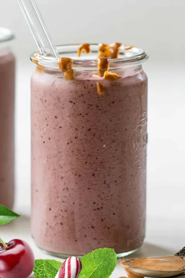 NutriBullet Pink Peppermint smoothie in a glass, on my kitchen counter, surrounded by fresh fruit and peppermint.