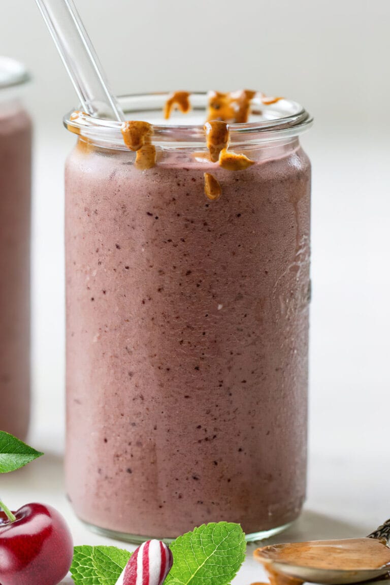 NutriBullet Pink Peppermint smoothie in a glass, on my kitchen counter, surrounded by fresh fruit and peppermint.