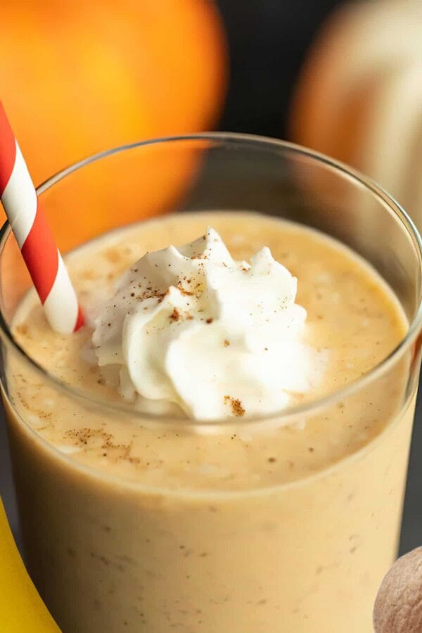 NutriBullet Pumpkin Banana smoothie in a glass, on my kitchen counter, surrounded by fresh fruit and vegetables.