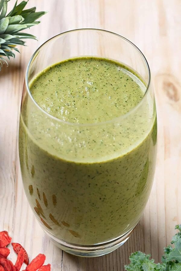 NutriBullet Spring Into Spring smoothie in a glass, on my kitchen counter, surrounded by fresh fruit and vegetables.