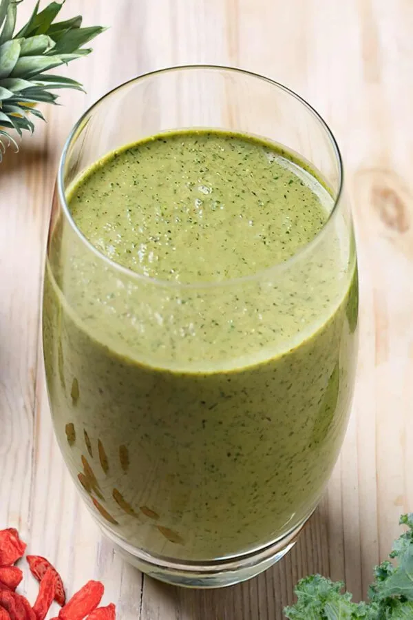 NutriBullet Spring Into Spring smoothie in a glass, on my kitchen counter, surrounded by fresh fruit and vegetables.