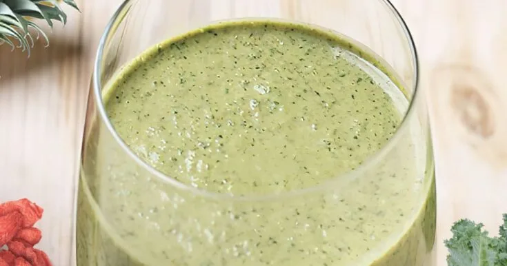 NutriBullet Spring Into Spring smoothie in a glass, on my kitchen counter, surrounded by fresh fruit and vegetables.
